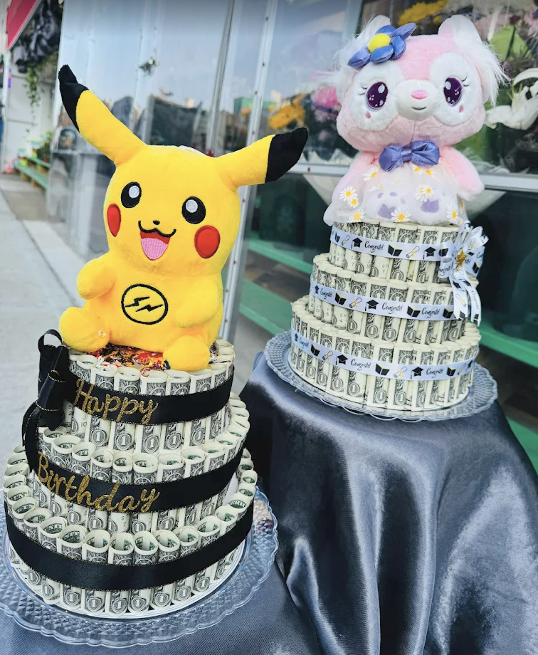 Two tiered money cakes topped with Pikachu and a pink plush