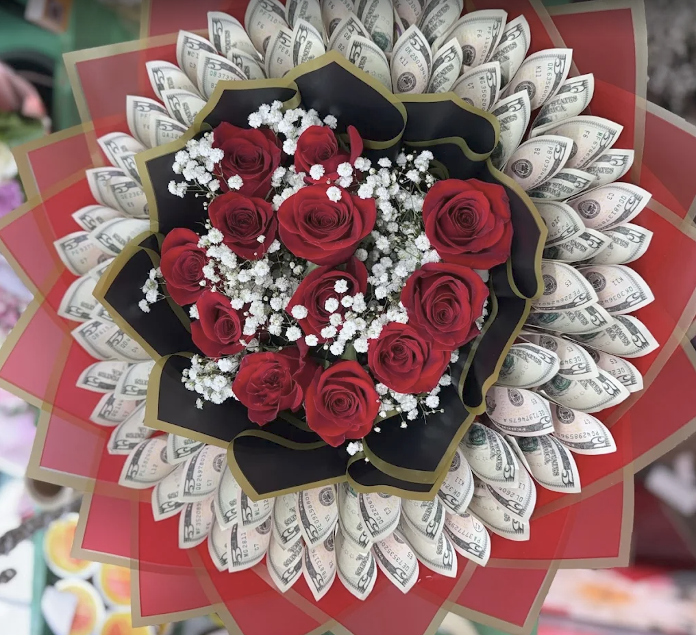 Red roses and baby's breath surrounded by folded dollar bills