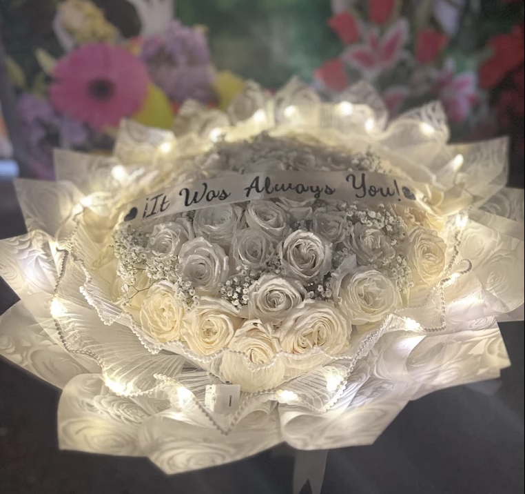 White rose bouquet with fairy lights and an It Was Always You sash